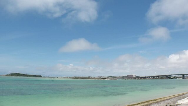 TOMIGUSUKU, OKINAWA, JAPAN - AUGUST 2021 : View of Senaga island and beach (Ocean or sea) in daytime. Clear blue summer sky and clouds. Holiday, vacation and resort concept video. Time lapse shot.