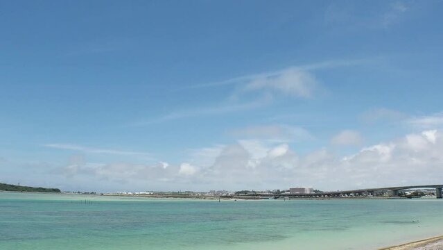 TOMIGUSUKU, OKINAWA, JAPAN - AUGUST 2021 : View of Senaga island and beach (Ocean or sea) in daytime. Clear blue summer sky and clouds. Holiday, vacation and resort concept video. Time lapse shot.