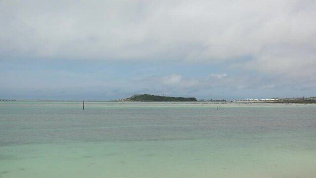 TOMIGUSUKU, OKINAWA, JAPAN - AUGUST 2021 : View of Senaga island and beach (Ocean or sea) in daytime. Clear blue summer sky and clouds. Holiday, vacation and resort concept video.