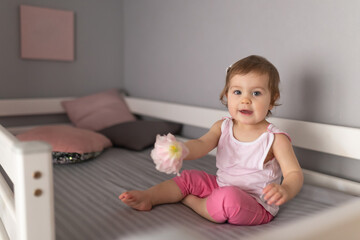 Cute little girl smiling sitting on the bed at home. The cheerful laughter of a small child