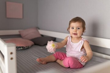 Fototapeta premium Cute little girl smiling sitting on the bed at home. The cheerful laughter of a small child
