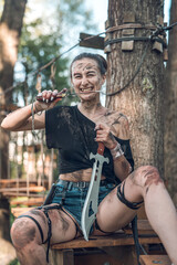 beautiful young girl in short shorts and a T-shirt smeared with swamp holds a dagger