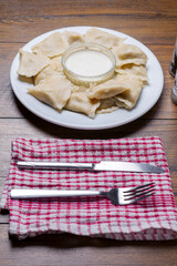 Serving of Polish dumplings on a wooden table and fork and knife on a red and white towel