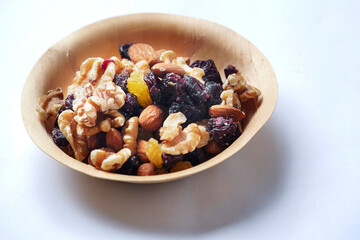 Mix fruit and nut mix in a small wooden cup on a white background. Healthy choice for energy. Raisins, walnut, almond in a bowl. Nature product