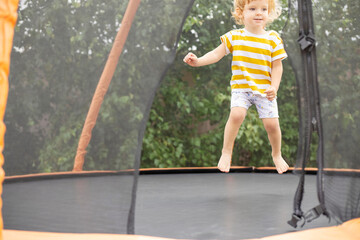 Child is jumping on a big trampoline outdoors in a park. Children outdoors activity