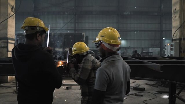 Welder workers working together in team fusing heavy metal in a truck production line factory manufacturing company in asia