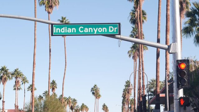 Palm trees and blue sky, Palm Springs resort city near Los Angeles, street road sign, semaphore traffic lights on crossroad. California desert valley summer road trip on car, travel USA. Indian Canyon