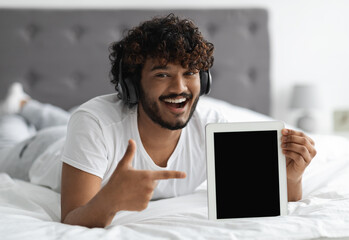 Cheerful young indian man showing digital tablet with blank screen