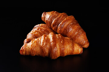 Several croissants lie on a black matte background.