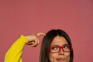 half portrait of a young woman with glasses scratching her head