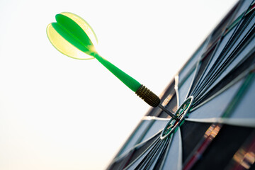 Close up shot green darts arrows in the target center on sky background. Business target or goal...