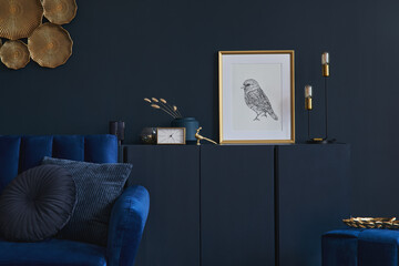 Creative composition of glamour living room interior design with mockup poster frame, wooden commode, lamp and elegant personal accessories. Dark blue wall. Home staging. Template. Copy space.