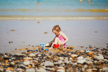 Toddler girl playing on the sand beach at Atlantic coast of Brittany, France