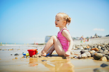 Toddler girl playing on the sand beach at Atlantic coast of Brittany, France