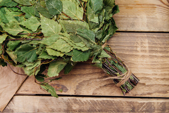 A dry birch broom lies on a wooden background. Accessories for baths and saunas.Natural, eco-friendly materials.