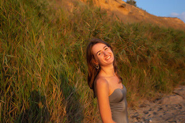 young beautiful woman in a halter swimsuit walks along the beach at sunset