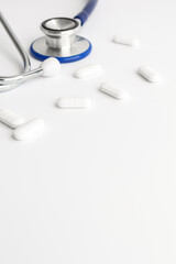 Stethoscope and white pills on white background. Copy space for a text 