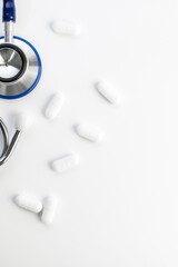 Stethoscope and white pills on white background. Medical help, cardiology care, health concept 