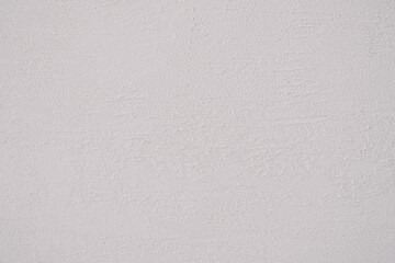 The uneven white wall's texture.