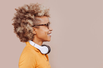 Side view of cheerful young latin american afro woman listening to music with earphones, wearing...
