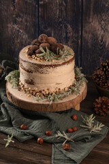 Delicious naked chocolate and hazelnuts cake on table rustic wood kitchen countertop.