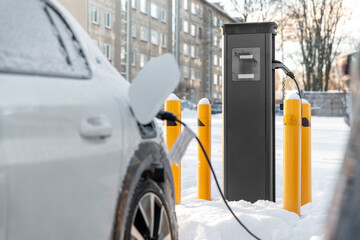 vehicle, power and green energy concept - close up of electric car charging battery in winter