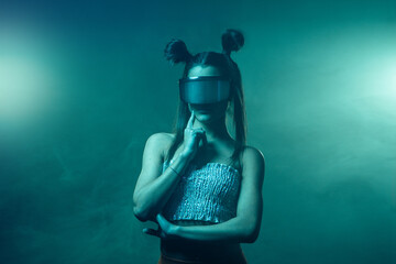 Portrait of beautiful cyber model woman posing wearing futuristic glasses on head with neon light in a virtual tech environment