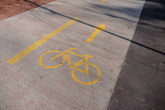Bicycle sign with an arrow painted on road surface in yellow paint.