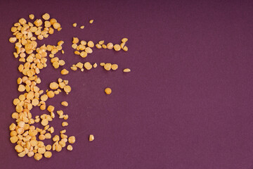 yellow pea grain texture on burgundy velvet background