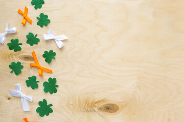 Flat lay for saint Patrick's day. Paper clover leaves with bows on wooden background