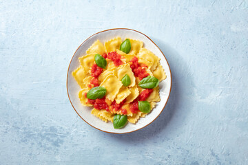 Ravioli with tomato sauce and fresh basil on a plate, shot from the top. Simple healthy Italian dish