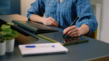Woman photographer retouching photos with graphic tablet and stylus at photography studio. Media artist using technology on computer and retouch gadget while editing pictures in office.