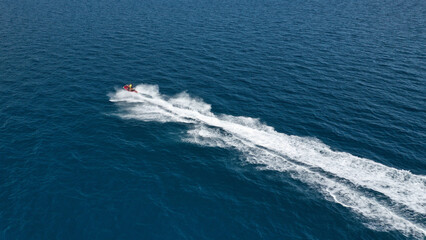 Aerial photo of jet ski with couple cruising in high speed in Caribbean tropical crystal clear deep blue waters
