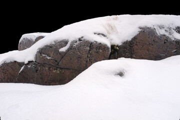 natural stone in snow isolated on black background