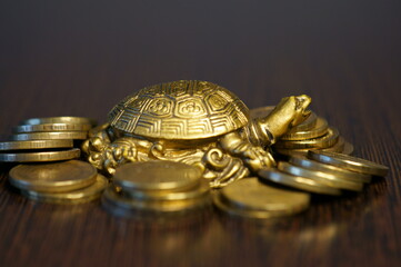 Metal turtle with coins on a dark background. A financial symbol of well-being and stability.