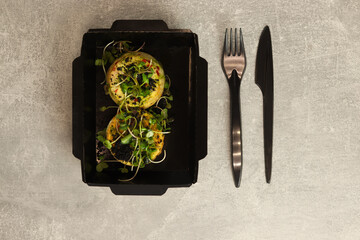  Healthy food delivery concept. Round omelette with vegetables. Restaurant dish delivery in eco paper boxes on gray background. Top view. Free space for text. 