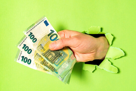 Businessman Breaking Through Green Paper With Bunch Of Euro Bills In Hand