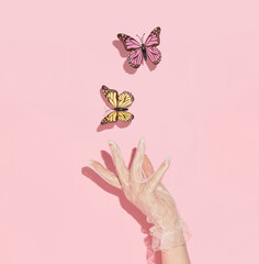 Spring creative layout with woman hand  and colorful butterflies  on pastel pink  background. 80s,...