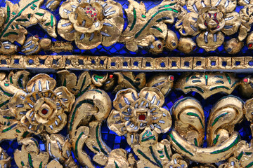 Fototapeta na wymiar Golden Pattern at Wat Pho in Bangkok, Thailand with Floral Design of shapes and color. Vintage thai golden pattern with gems. Asian golden ornament in Thailand. Traditional decorative background