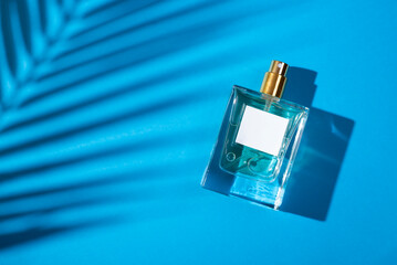 Transparent bottle of perfume with label on a blue background. Fragrance presentation with...
