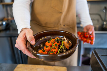 Chef showing some organic cherry tomatoes steamed and grilled cooked in a food truck.