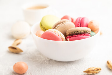 Different colors macaroons and chocolate eggs in ceramic bowl, cup of coffee on gray concrete background. side view, close up. - Powered by Adobe
