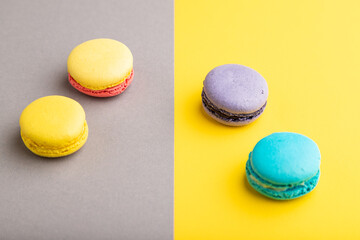 Yellow, purple and blue macaroons on trendy gray and yellow background. side view, copy space.