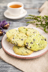 Green cookies with chocolate and mint with cup of green tea on gray wooden background. side view, close up, selective focus.