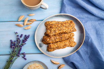Crumble cookies with seasme and almonds on ceramic plate with cup of coffee on blue wooden background. top view, close up.