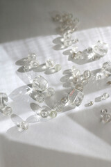 Various transparent beads on white background, illuminated by sunlight and reflectiing light. Selective focus.
