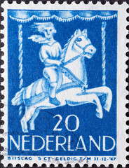 Netherlands - circa 1946: a postage stamp from the Netherlands , showing a Child in Merry-go-round. child postage stamp 1946 , blue