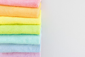 New folded microfiber cloth for cleaning in seven rainbow colors on gray background. Cleaning micro...