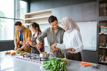 friend cooking together in the kitchen while looking at online course from tablet pc