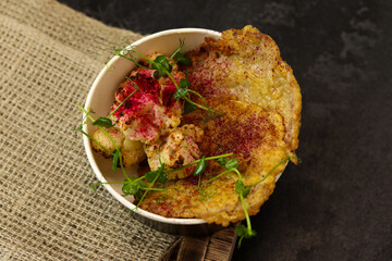 Healthy food delivery concept. Beef schnitzel with cauliflower in an eco paper container on a black background with burlap. Restaurant dish delivery. Top view. Free space for text